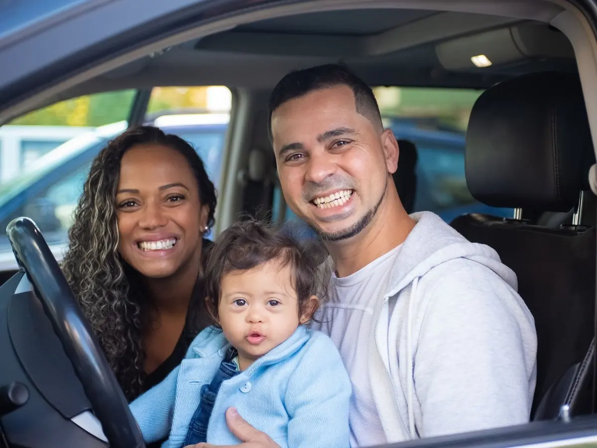 Familia sonriendo dentro de su auto